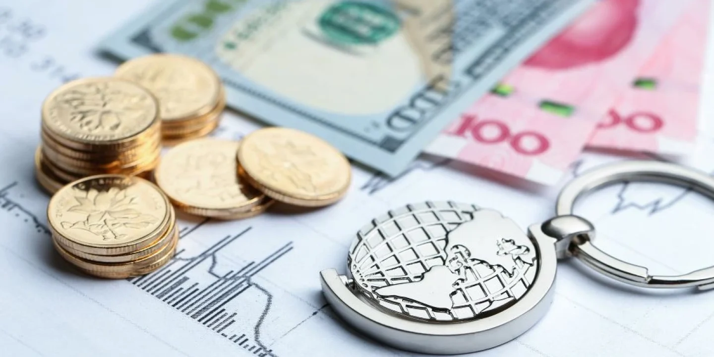 Coins and banknotes on a financial chart with a globe keychain, illustrating global finance at a glance.
